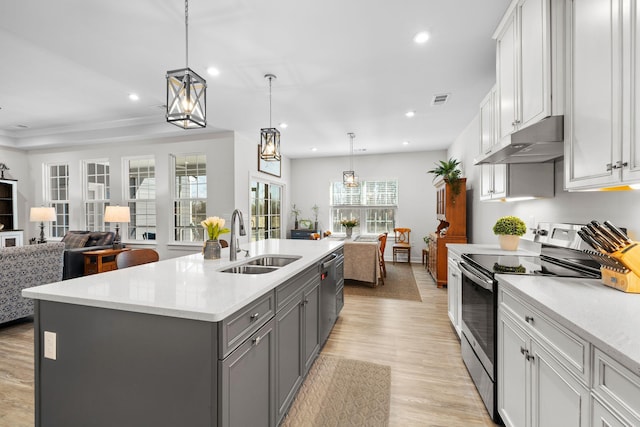 kitchen featuring stainless steel appliances, gray cabinets, open floor plan, a sink, and under cabinet range hood