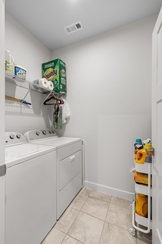 washroom with light tile patterned floors, laundry area, separate washer and dryer, visible vents, and baseboards