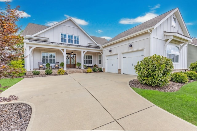 modern inspired farmhouse with a garage, driveway, a porch, and board and batten siding