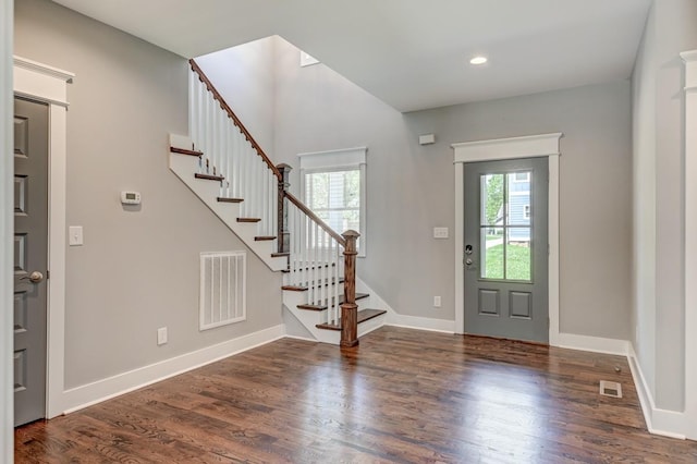 foyer with visible vents, stairway, baseboards, and wood finished floors