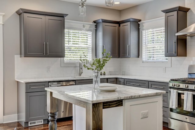 kitchen with tasteful backsplash, light stone countertops, stainless steel appliances, wall chimney range hood, and a sink