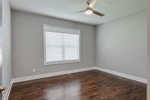 spare room featuring dark wood-type flooring, visible vents, ceiling fan, and baseboards