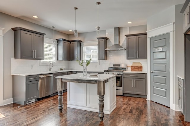 kitchen with dark wood-style flooring, tasteful backsplash, appliances with stainless steel finishes, a sink, and wall chimney exhaust hood