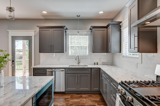 kitchen with stainless steel appliances, plenty of natural light, a sink, and wall chimney range hood