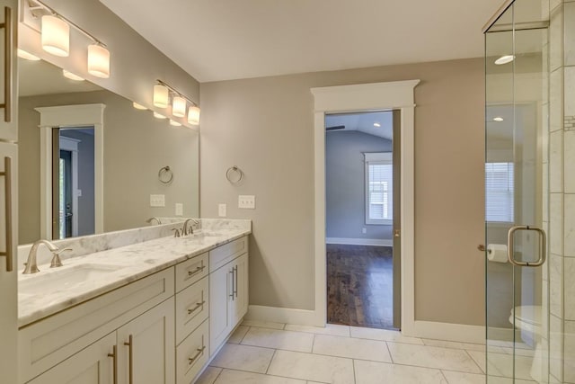 bathroom with double vanity, a shower stall, a sink, and tile patterned floors