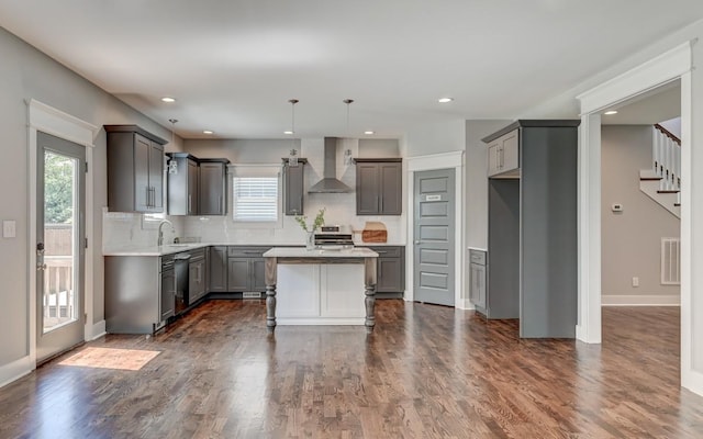 kitchen featuring visible vents, dark wood-style floors, wall chimney exhaust hood, a kitchen island, and appliances with stainless steel finishes