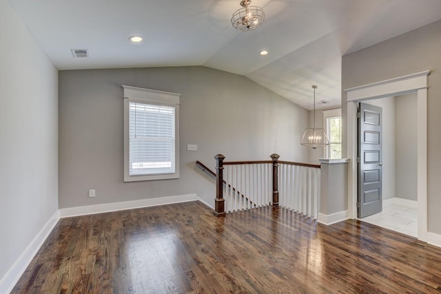 additional living space featuring lofted ceiling, wood finished floors, visible vents, and an inviting chandelier