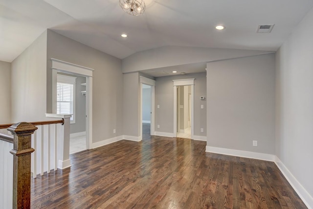 spare room with baseboards, visible vents, vaulted ceiling, and wood finished floors