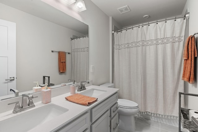 bathroom featuring toilet, visible vents, a sink, and tile patterned floors