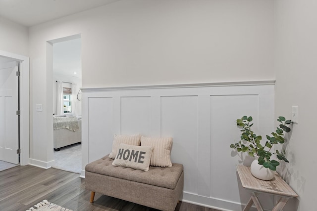 sitting room with a wainscoted wall, wood finished floors, and a decorative wall