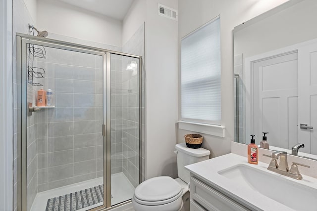 full bathroom with toilet, a stall shower, visible vents, and vanity