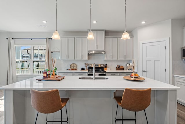 kitchen with a sink, light countertops, backsplash, and a kitchen breakfast bar