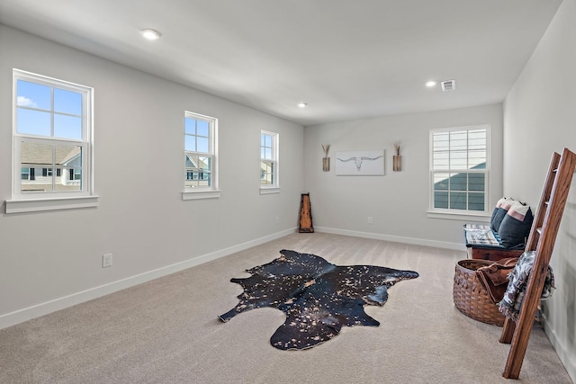 living area featuring light carpet, a healthy amount of sunlight, visible vents, and baseboards