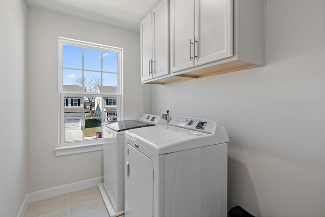 washroom featuring cabinet space, light tile patterned floors, baseboards, and independent washer and dryer