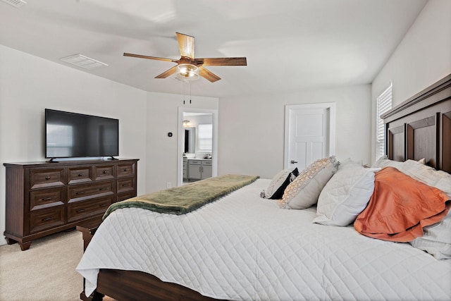 bedroom with light carpet, ensuite bath, visible vents, and ceiling fan