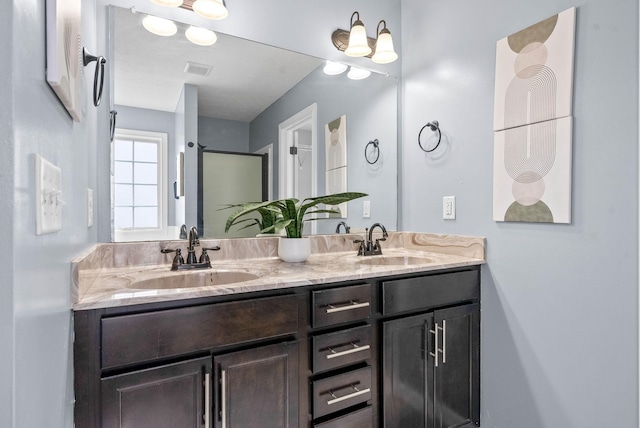 bathroom featuring double vanity, visible vents, a sink, and a shower with shower door