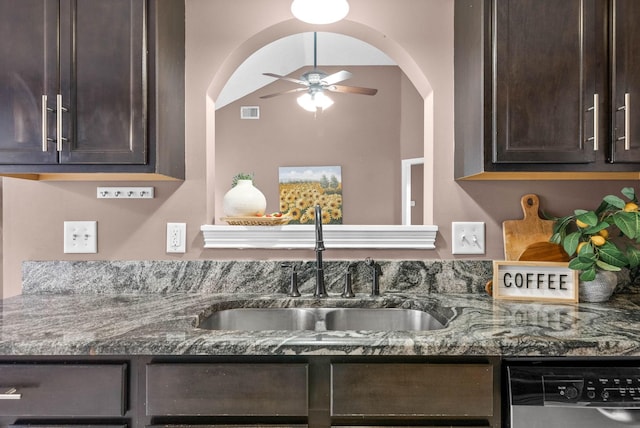 kitchen featuring dishwashing machine, dark brown cabinets, dark stone countertops, and a sink