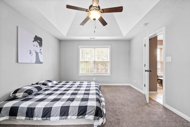 carpeted bedroom with a raised ceiling, visible vents, a ceiling fan, a textured ceiling, and baseboards