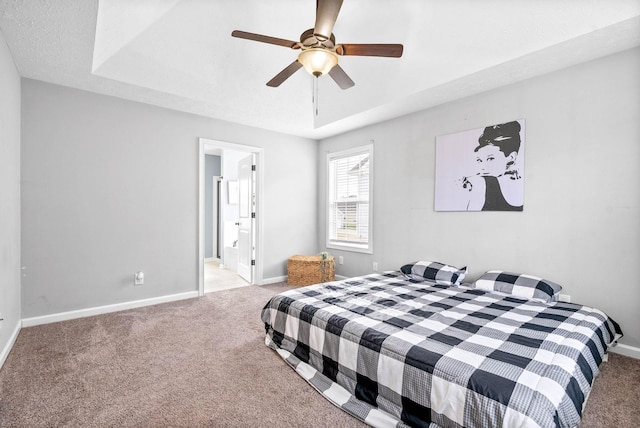 carpeted bedroom featuring a ceiling fan, a tray ceiling, a textured ceiling, and baseboards