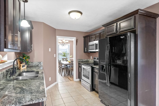 kitchen with light tile patterned floors, appliances with stainless steel finishes, a sink, dark brown cabinetry, and dark stone countertops