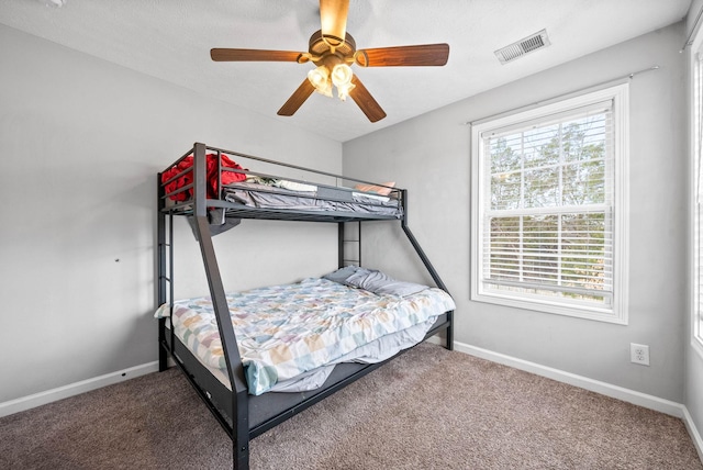 carpeted bedroom featuring a ceiling fan, visible vents, and baseboards