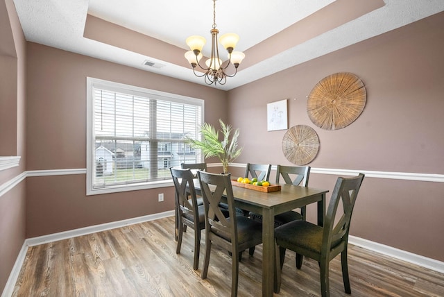 dining room with a tray ceiling, visible vents, and baseboards