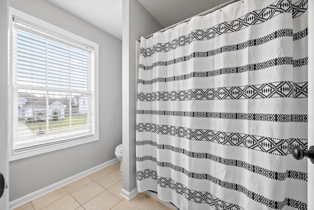 bathroom featuring a shower with curtain, tile patterned flooring, toilet, and baseboards