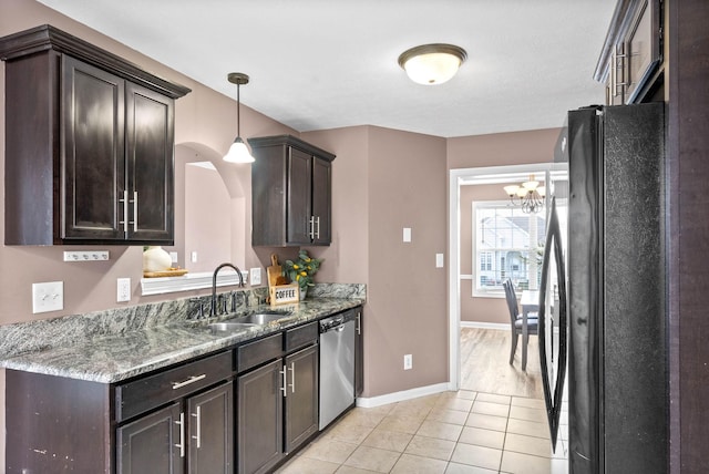 kitchen with a sink, dark brown cabinetry, stainless steel dishwasher, and freestanding refrigerator