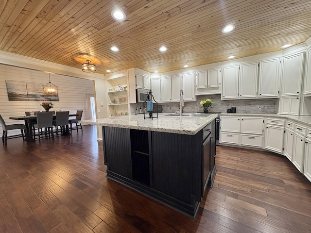 kitchen featuring white cabinets, stainless steel microwave, a sink, and open shelves