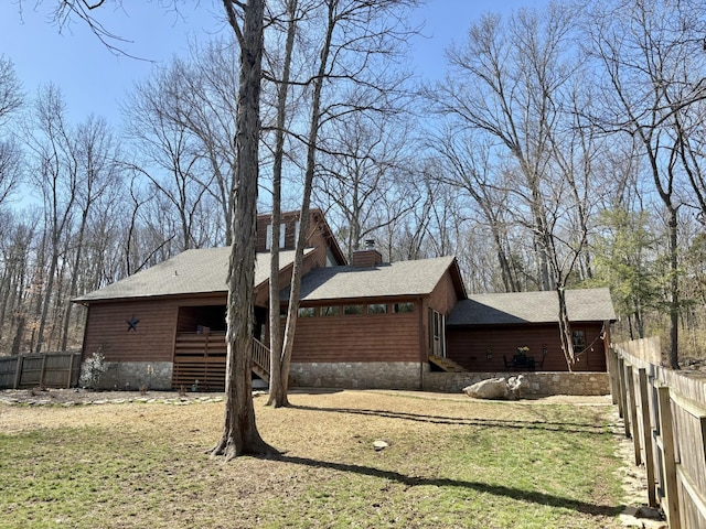 view of side of property featuring a chimney, fence, and a yard