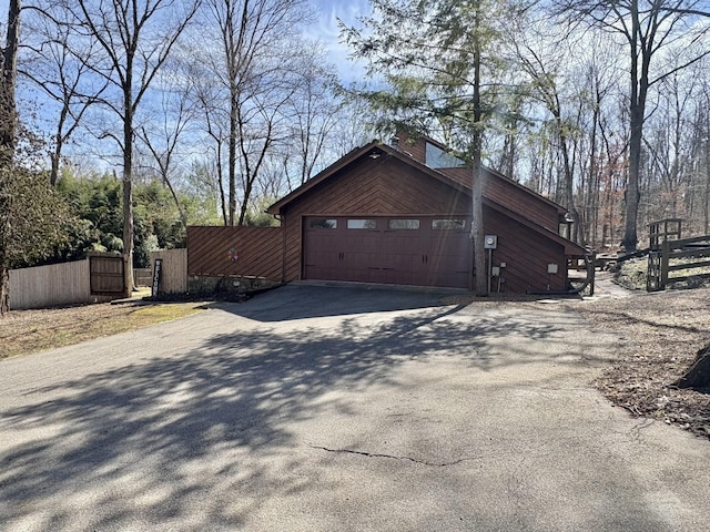 view of home's exterior with a gate, fence, and driveway