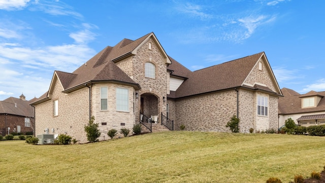 french country home with central AC, a front lawn, a shingled roof, and brick siding