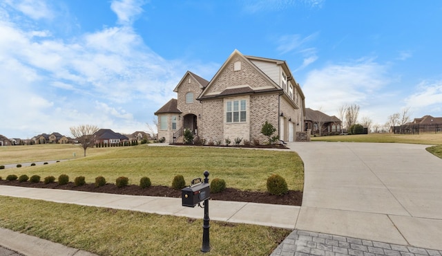 french country style house with a front yard, concrete driveway, brick siding, and an attached garage