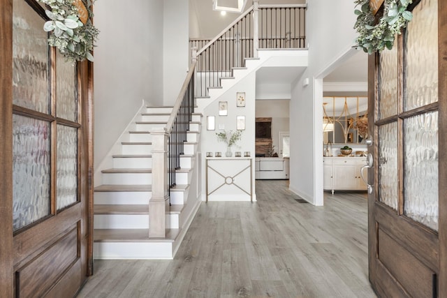 entrance foyer featuring stairway, wood finished floors, a towering ceiling, and crown molding