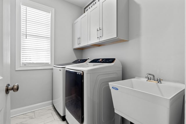 clothes washing area with marble finish floor, washer and clothes dryer, cabinet space, a sink, and baseboards