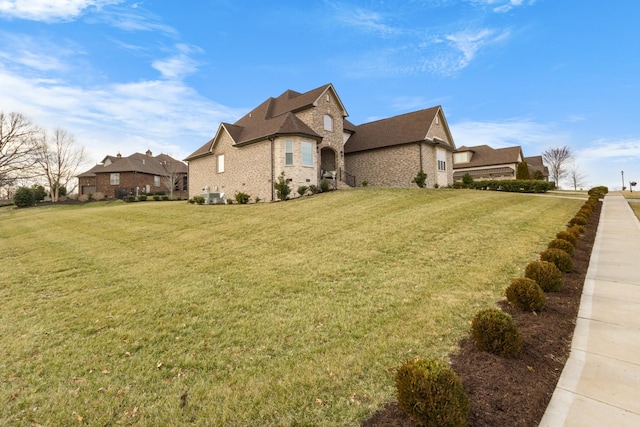 view of home's exterior with brick siding, central AC, and a yard