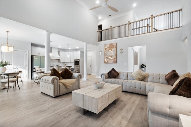 living area with light wood-style floors, decorative columns, baseboards, and a ceiling fan