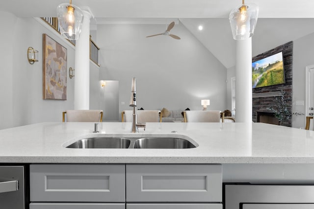 kitchen featuring light stone countertops, a fireplace, vaulted ceiling, and a sink