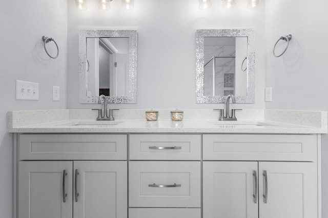 bathroom featuring double vanity, a shower, and a sink