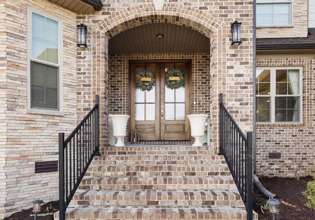 doorway to property with french doors, brick siding, and crawl space