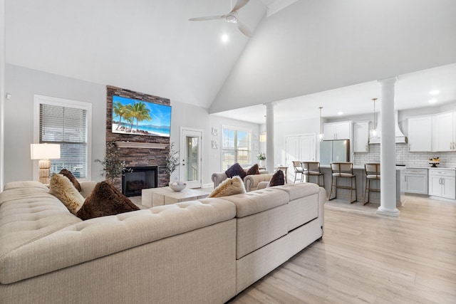 living room with light wood finished floors, decorative columns, high vaulted ceiling, and a ceiling fan