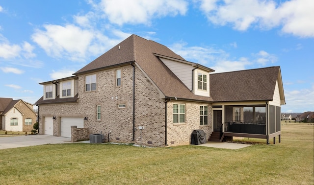 rear view of house with brick siding, a lawn, an attached garage, a sunroom, and driveway