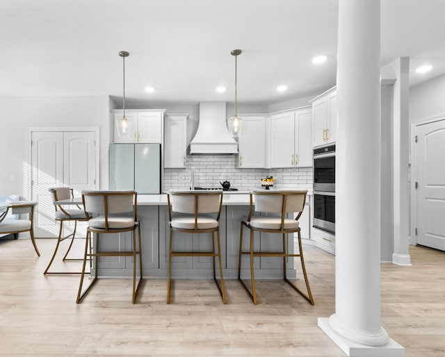 kitchen with light wood-style floors, backsplash, custom exhaust hood, and refrigerator