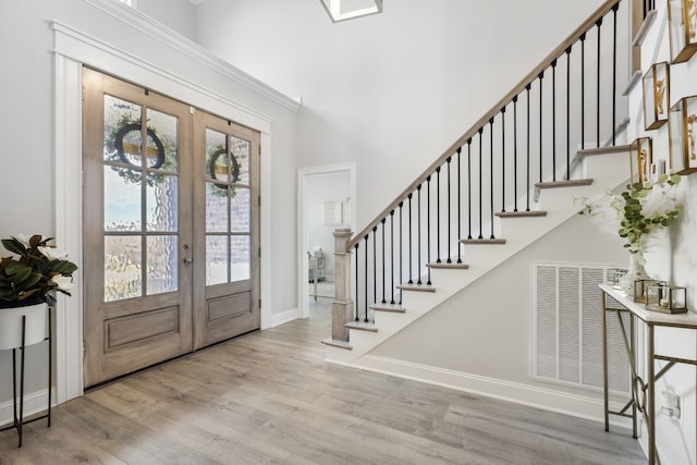 foyer entrance featuring stairs, french doors, baseboards, and wood finished floors