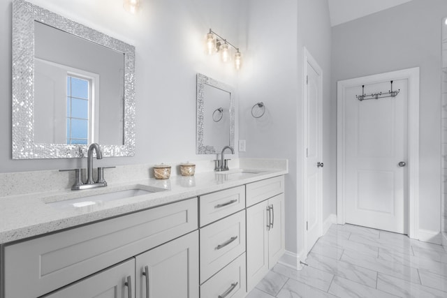 bathroom with double vanity, marble finish floor, baseboards, and a sink