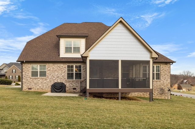 rear view of property featuring a sunroom, a shingled roof, a lawn, and brick siding