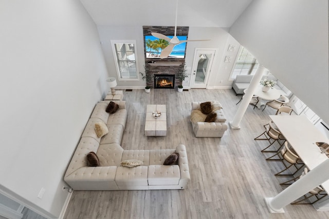 living room with ceiling fan, a fireplace, baseboards, and wood finished floors