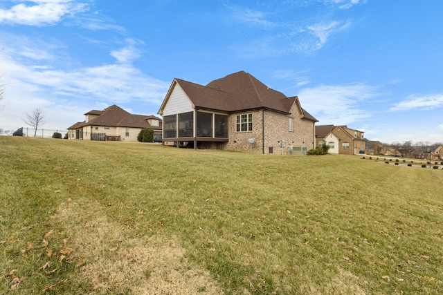 back of house with a sunroom, a lawn, and brick siding