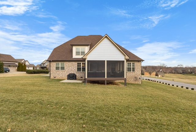 rear view of house featuring crawl space, a sunroom, a lawn, and brick siding