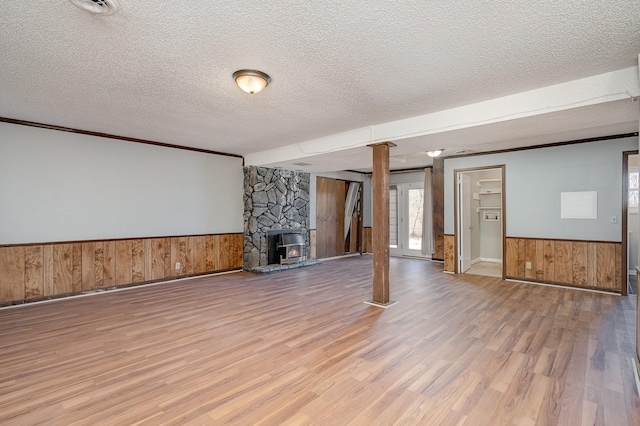 below grade area featuring a wainscoted wall, wooden walls, a textured ceiling, and wood finished floors